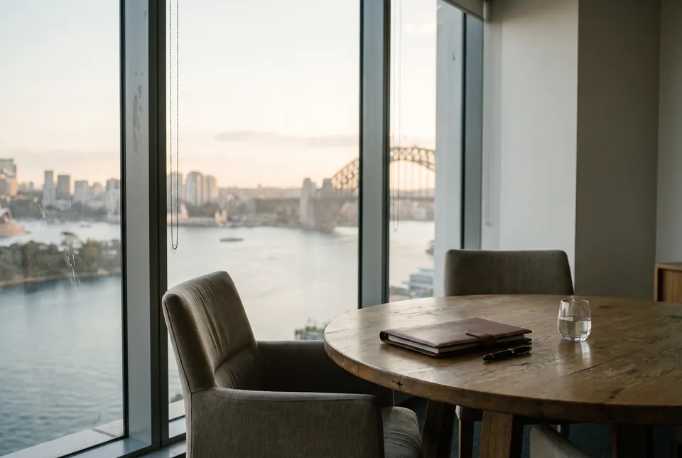 A calm meeting room with a round oak table, looking out over Sydney Harbour.